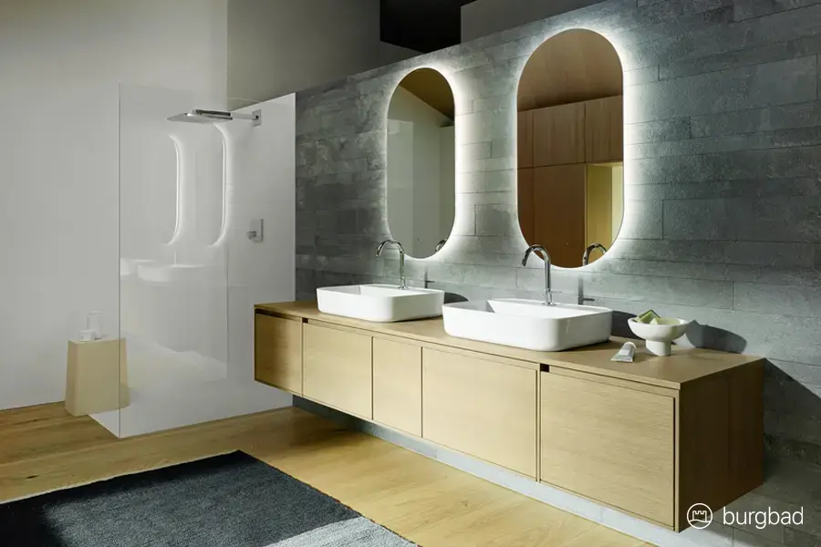 Modernes Badezimmer mit Doppelwaschtisch, beleuchteten Spiegeln und begehbarer Dusche – Komplettbadsanierung von Der Bäderbauer